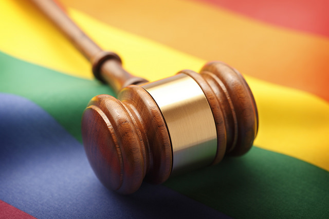 A gavel resting on a rainbow flag which is a symbol of the LGBT movement. Image illustrates the many legal challenges associated with the LGBT movement.