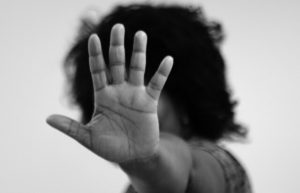 Imagem em preto e branco de uma mulher com a mão estendida para frente, sinalizando um “Pare”.