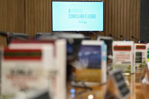 Foto ilustrativa do plenário do CNJ onde ao fundo tem telão escrito 10º Prêmio Conciliar é Legal