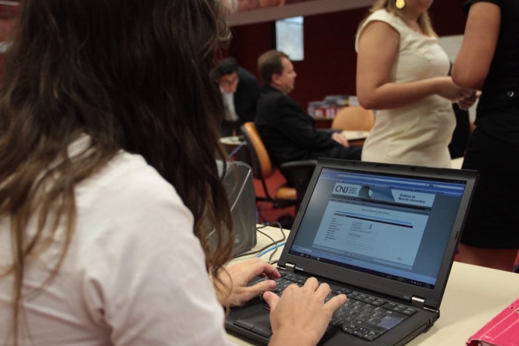 Foto de mulher usando computador para se inscrever em curso do CNJ