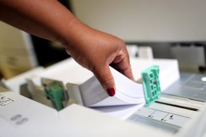 Foto mostra pessoa segurando resma de folhas A4.