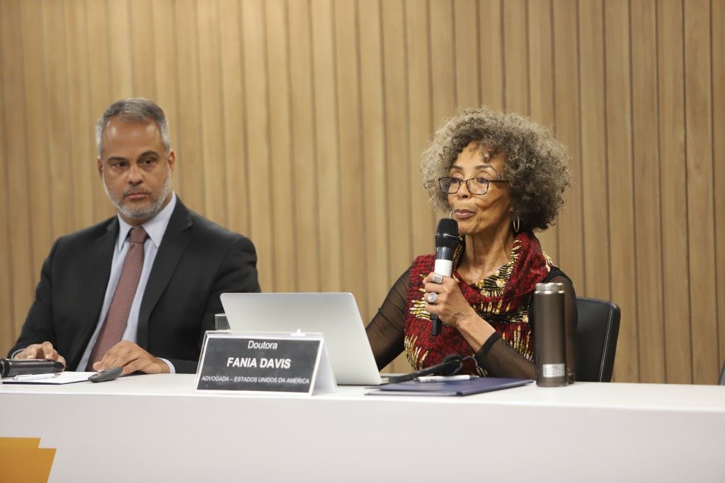 Foto de mesa durante a 2ª Conferência do Seminário Internacional Judiciário, sistema penal e sistema socioeducativo, com a advogada dos EUA, Dra. Fania Elizabeth Davis, falando enquanto é observada pelo . Juíz auxiliar da presidência do CNJ, Dr. Carlos Gustavo Direito.