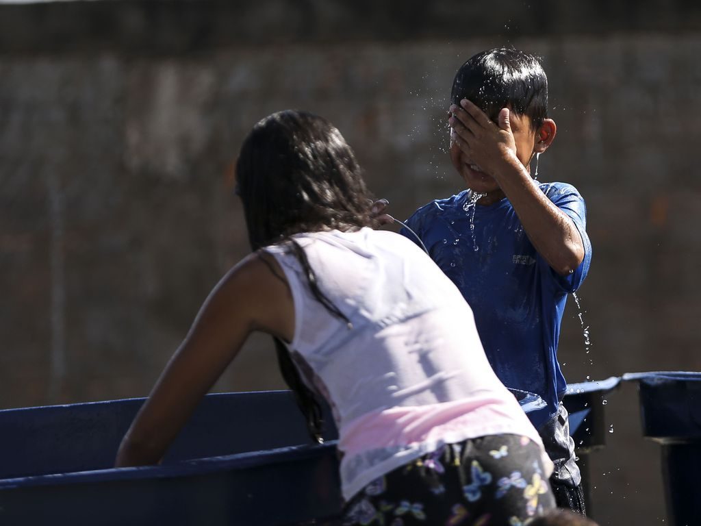 Duas crianças imigrantes da Venezuela bricam com água em abrigo em Boa Vista (RR)