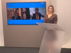 Foto de still do programa, com a apresentadora Mariana Xavier à frente de telão com os dois entrevistados da edição