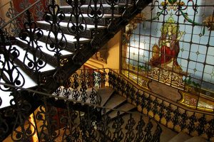 Foto mostra escadaria antiga, com vitrais nas paredes, dentro do Centro Cultural do TRF2.