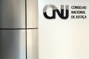 Foto do plenário do Conselho Nacional de Justiça (CNJ), com detalhe com a marca do CNJ na parede.