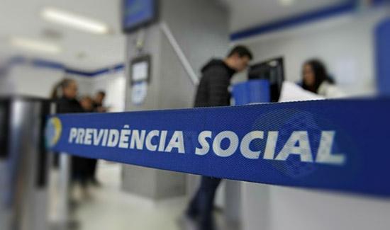 Foto interna de agência da Previdência Social, com destaque a divisor de fila onde se lê "Previdência Social".