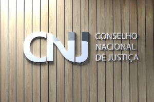 Foto da logomarca do CNJ dentro do auditório, onde se lê CNJ, Conselho Nacional de Justiça
