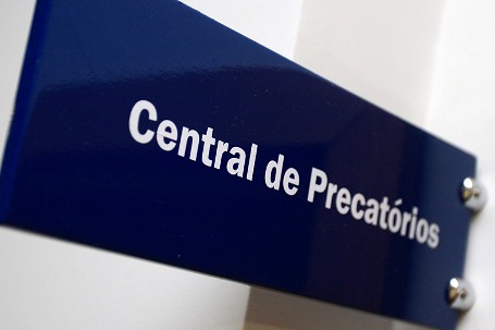 Foto mostra uma placa na parede de um tribunal, onde se lê "Central de Precatórios"