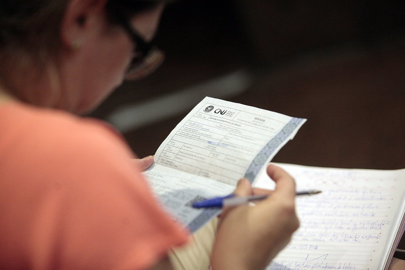 Foto mostra uma mulher segurando o registro do apostilamento eletrônico.