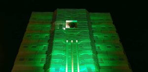 Foto da fachada da sede do Fórum Trabalhista de Campo Grande (MS) iluminada de verde.