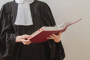 Foto mostra detalhe de uma juíza segurando um livro aberto.