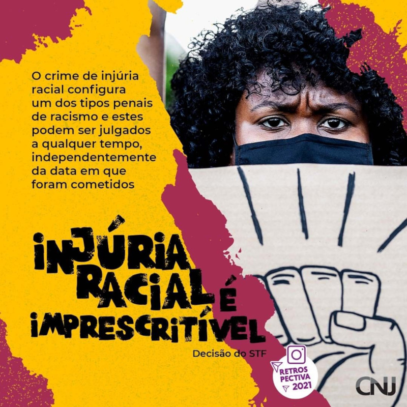 Entre grafismos disformes, foto de mulher negra usando máscara e segurando um cartaz com o desenho de uma mão com punho fechado em sinal de protesto. Texto: Injúria racial é imprescritível. Conforme artigo 5º, inciso LXII, da Constituição Federal, ofensas por conta da raça equivale a racismo e não tem perdão. Decisão do STF. Retrospectiva 2021.