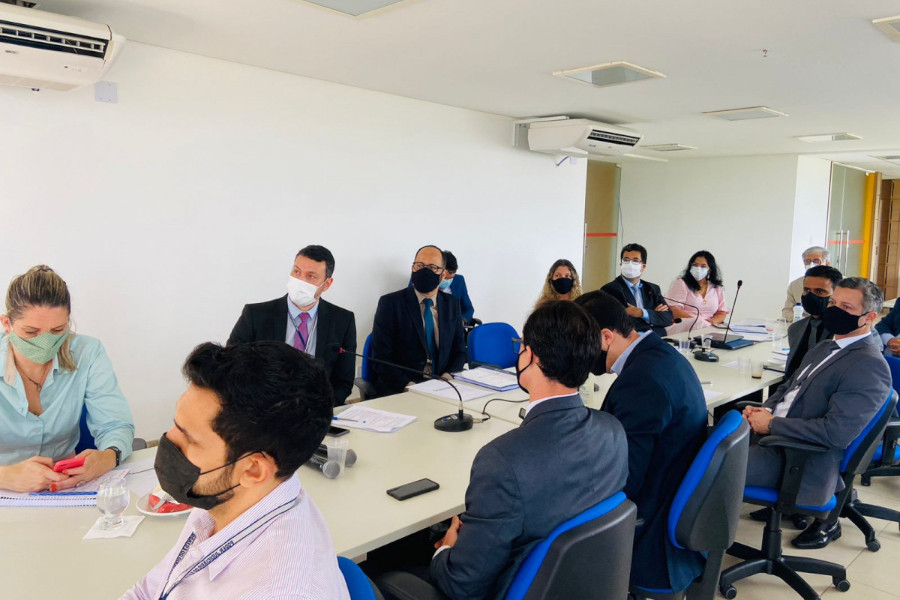 Foto mostra 13 representantes do TJBA sentados em uma sala, com uma mesa central, participando da reunião.