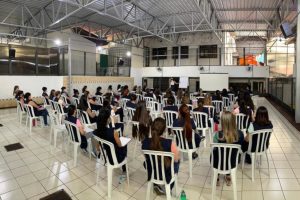 Foto mostra momento da semana pedagógica, onde se vê as educadoras sentadas e acompanhando uma palestra.