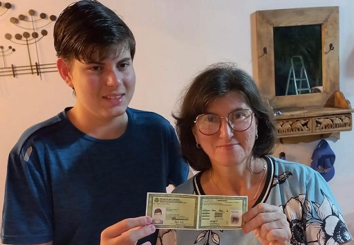 Foto mostra Kátia Berta segurando o RG na mão ao lado de seu filho.