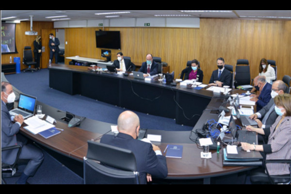 Foto geral da reunião, com as pessoas participantes sentadas em mesa em U.