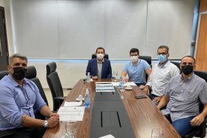 Foto mostra participantes do encontro, sentados em volta de uma mesa de reunião.