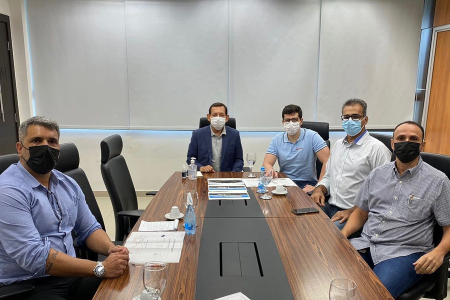 Foto mostra participantes do encontro, sentados em volta de uma mesa de reunião.
