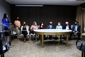 Foto mostra momento do evento de renovação da parceria, com as pessoas participantes sentadas em uma mesa.