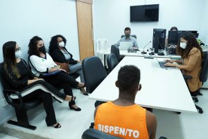 Foto mostra momento de audiência de custódia no Fórum de Palmas, com a pessoa custodiada e seus representantes sendo atendidos pelo serviço.