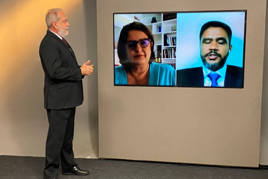 Foto mostra o apresentador do programa no estúdio, conversando por meio de telão com os dois entrevistados.