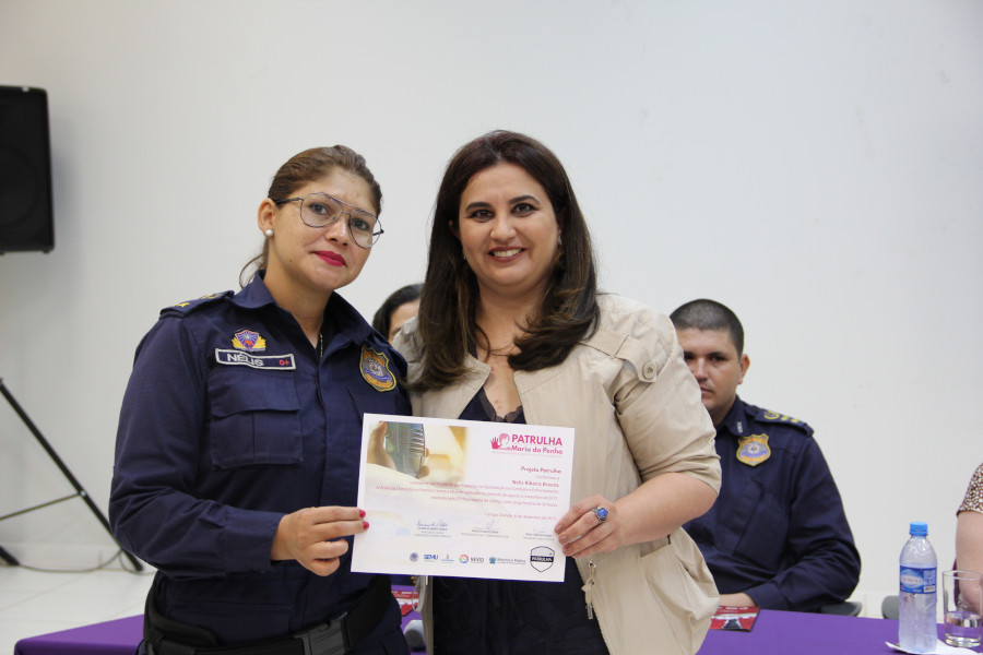 Foto mostra a promotora de Justiça Luciana Rabelo posando ao lado de uma guarda civil, com ambas segurando o certificado da capacitação.