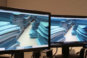 Foto mostra imagens de processos físicos em dois monitores de computador.