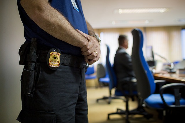 Foto mostra o detalhe de distintivo na cintura de agente de segurança da Justiça Federal.