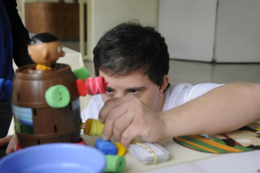 Foto mostra um homem com síndrome de Down utilizando um brinquedo.