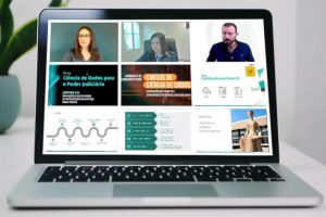 Foto mostra um notebook onde na tela se vê uma fotomontagem com diversos momentos do webinário de lançamento dos cursos.