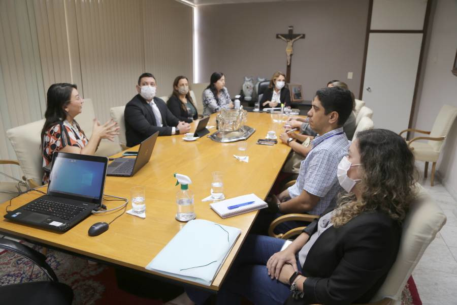 Foto de momento da reunião em uma sala do TJSE, com participantes sentados em volta de uma mesa.