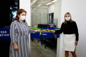 Foto mostra duas mulheres segurando uma fita nas cores da bandeira brasileira na porta de entrada da unidade reformada.