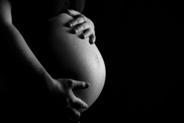 Foto mostra a silhueta de barriga de uma mulher grávida.