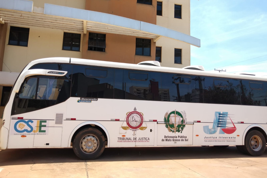 Foto mostra o ônibus da Justiça Itinerante do TJMS estacionado em frente a um prédio.