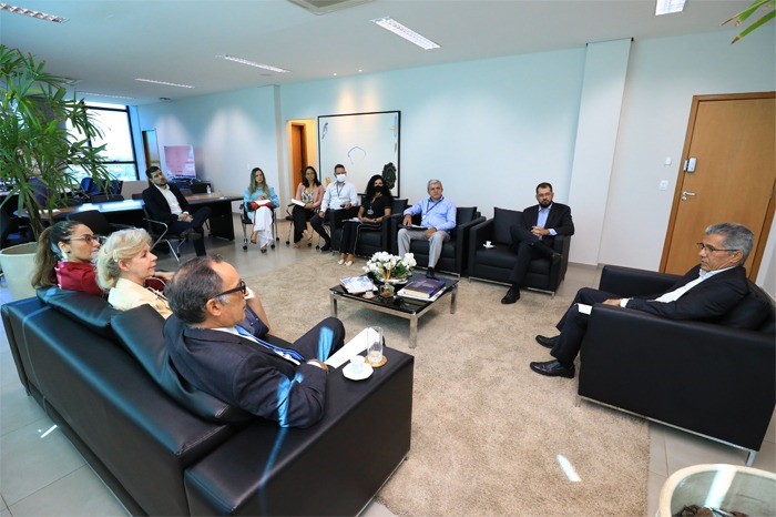 Foto mostra participantes da reunião sentados em poltronas e sofás e conversando em sala do TJTO.