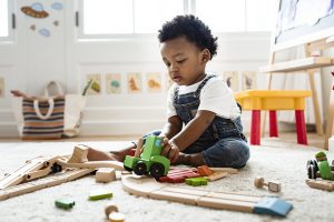 Criança brincando no chão com jogo de blocos