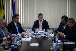 Foto em uma sala do TJAM mostra as pessoas sentadas em volta de uma mesa e conversando.