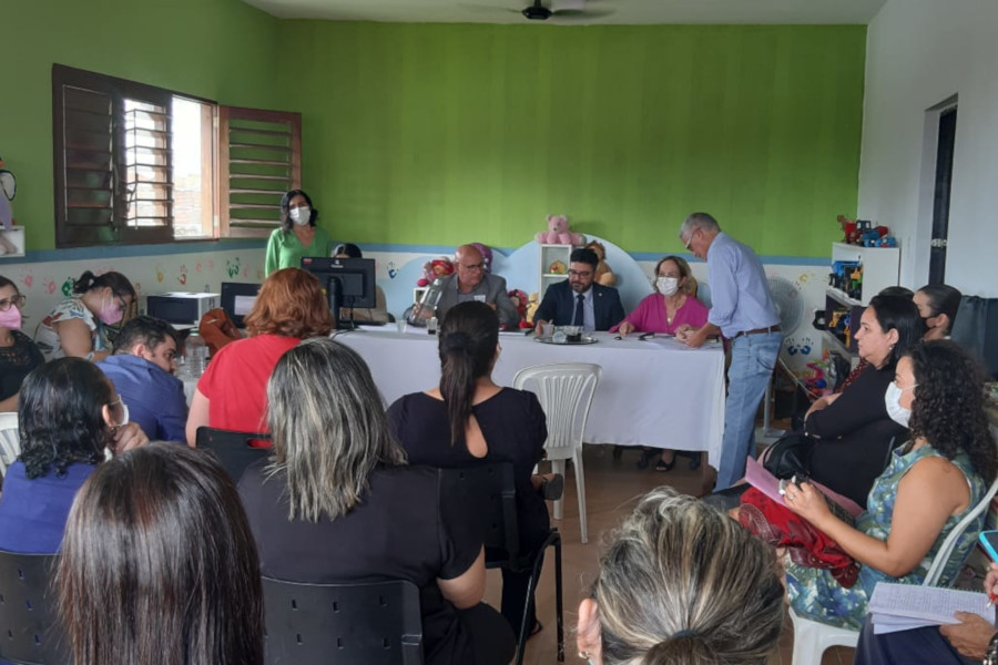 Foto mostra momento de audiência concentrada em unidade de acolhimento, com diversas pessoas sentadas em cadeiras e, á frente, juiz e auxiliares sentados atrás de uma mesa.