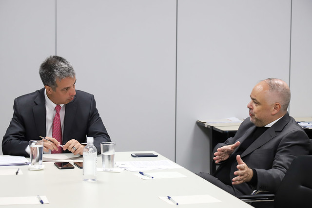 Foto mostra o conselheiro Mauro Martins e o o juiz Luís Geraldo Santana Lanfredi sentados em uma sala, em volta de uma mesa, conversando.