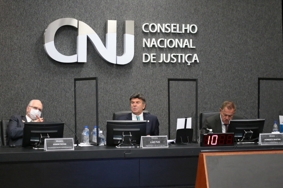 Foto da bancada principal do Plenário do CNJ, com o presidente do TSE, Edson Fachin, à esquerda; presidente do CNJ, Luiz Fux, ao centro; e presidente do STJ, Humberto Martins, à direita.