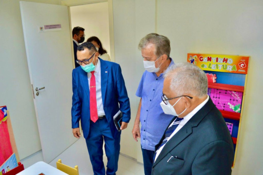 Foto mostra três homens olhando a estrutura da sala de depoimento especial.