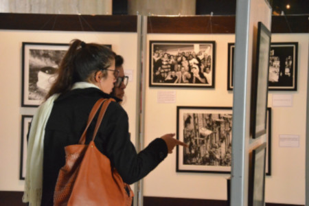 Duas mulheres visitando uma das exposições do Memorial, comentando e apontado para uma das fotos.