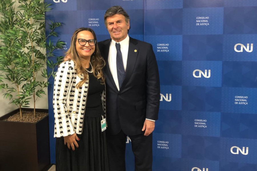 Foto mostra o ministro Fux e a presidente do TRT14 posando em frente a um painel com a marca do CNJ.