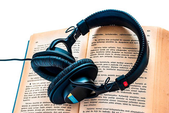 Foto mostra um headphone sobre um livro aberto.