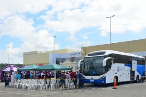 Foto mostra ônibus da Justiça Itinerante estacionado em frente ao Fórum de Paulista (PE), com tendas montadas em sua volta e diversas pessoas.