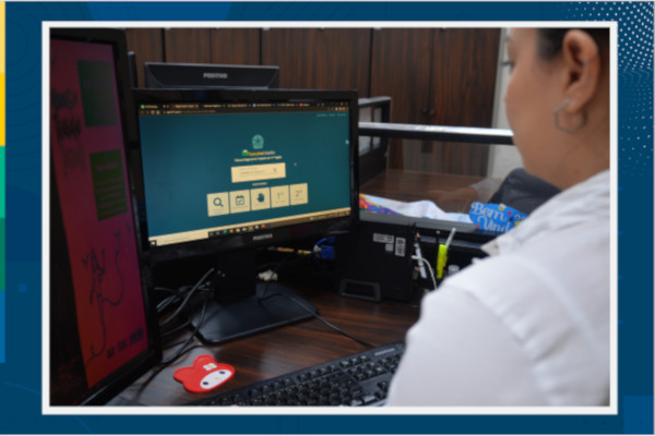 Foto mostra uma mulher, sentada em frente a um computador em um escritório e acessando a Consulta Cidadão.