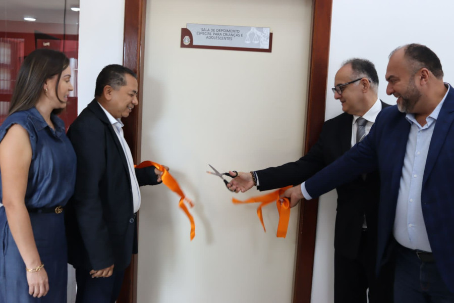 Foto mostra momento em que o juiz Carlos Jardim, acompanhado da servidora Valda Calderaro e de outros dois homens, corta a fita colocada na porta de entrada da Sala de Depoimento Especial, em um gesto simbólico de inauguração do espaço.