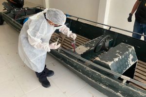 Foto mostra um profissional da perícia analisando o barco.