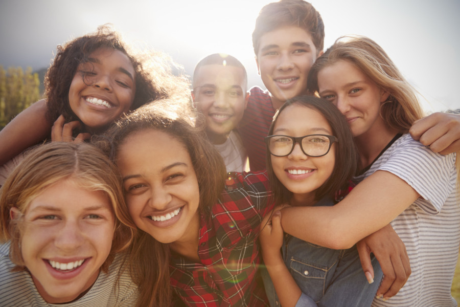 Foto mostra adolescentes abraçados e sorrindo.